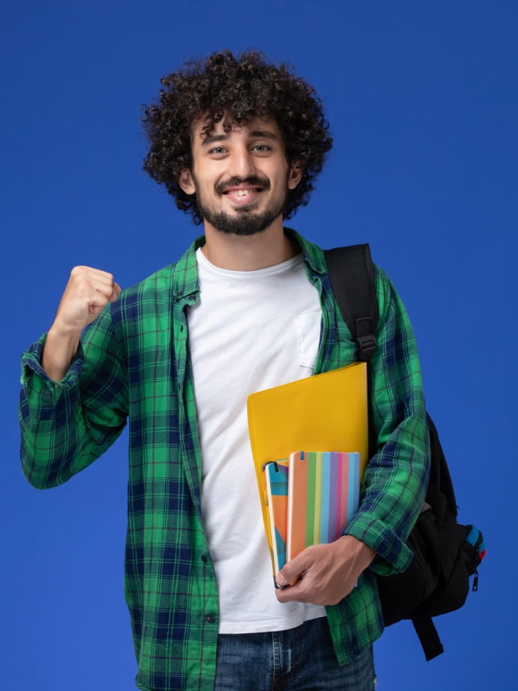 front-view-male-student-wearing-black-backpack-holding-copybooks-files-blue-wall